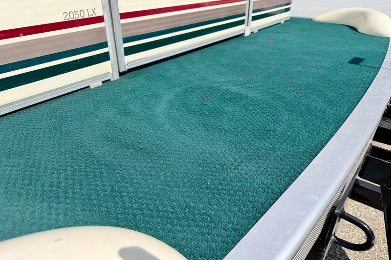 Slide: The Image of 2001 Bennington 2050 LX boat deck with green carpet and striped side panel. - 14