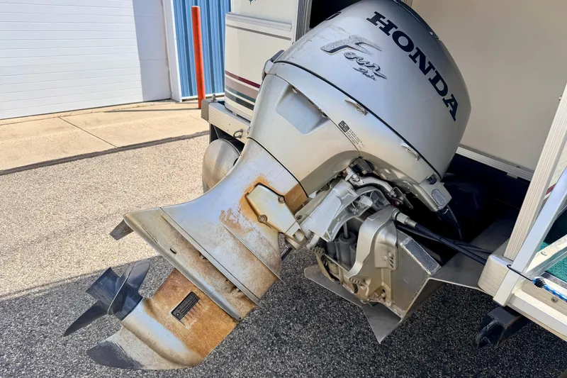 Slide: The Image of Honda outboard motor on a 2001 Bennington 2050 LX boat, parked on pavement. - 17