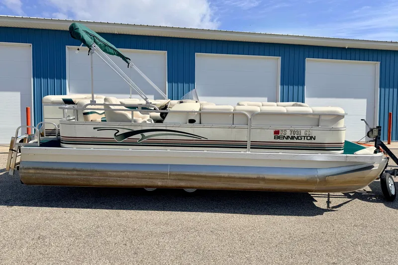 Slide: The Image of 2001 Bennington 2050 LX pontoon boat parked outside blue garage doors. - 2