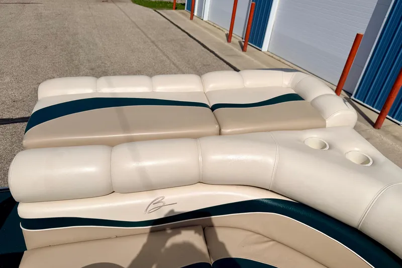 Slide: The Image of Bennington 2050 LX 2001 boat seating with beige and green upholstery, featuring cup holders. - 24