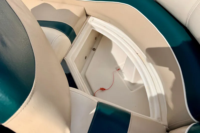 Slide: The Image of Open storage compartment in 2001 Bennington 2050 LX boat seat, featuring white and teal upholstery. - 29