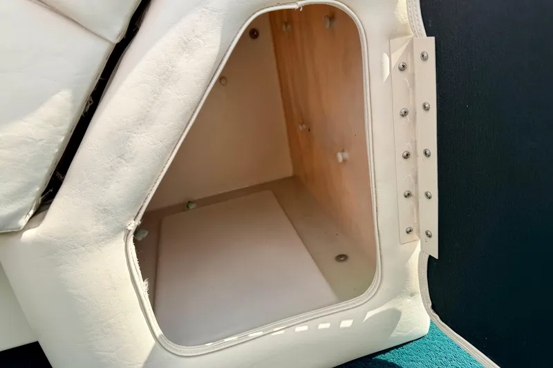 Slide: The Image of Storage compartment in a 2001 Bennington 2050 LX boat, featuring white upholstery and wooden interior. - 44