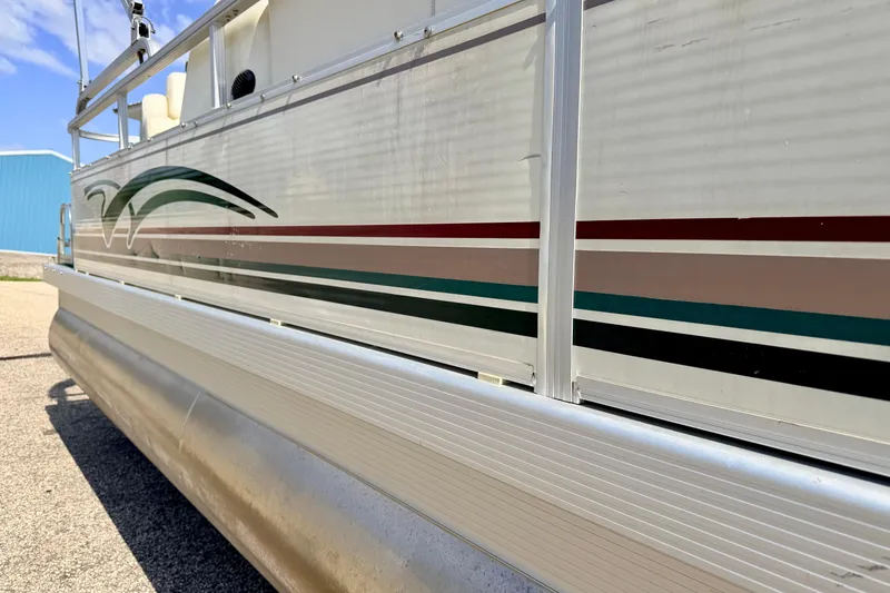 Slide: The Image of 2001 Bennington 2050 LX pontoon boat with colorful side stripes, docked outdoors. - 5