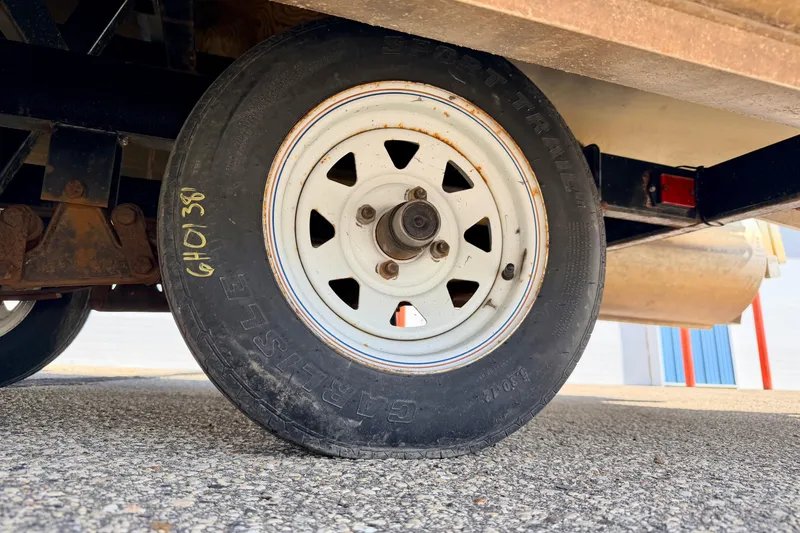 Slide: The Image of Trailer wheel of a 2001 Bennington 2050 LX on asphalt surface. - 74