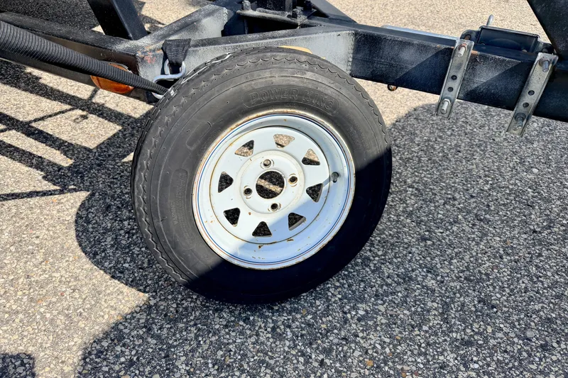 Slide: The Image of Trailer wheel on a Bennington 2050 LX, 2001 model, parked on asphalt. - 9