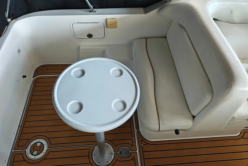 Slide: The Image of 2001 Sea Ray Sundancer 260 interior with white seating and round table on teak flooring. - 28