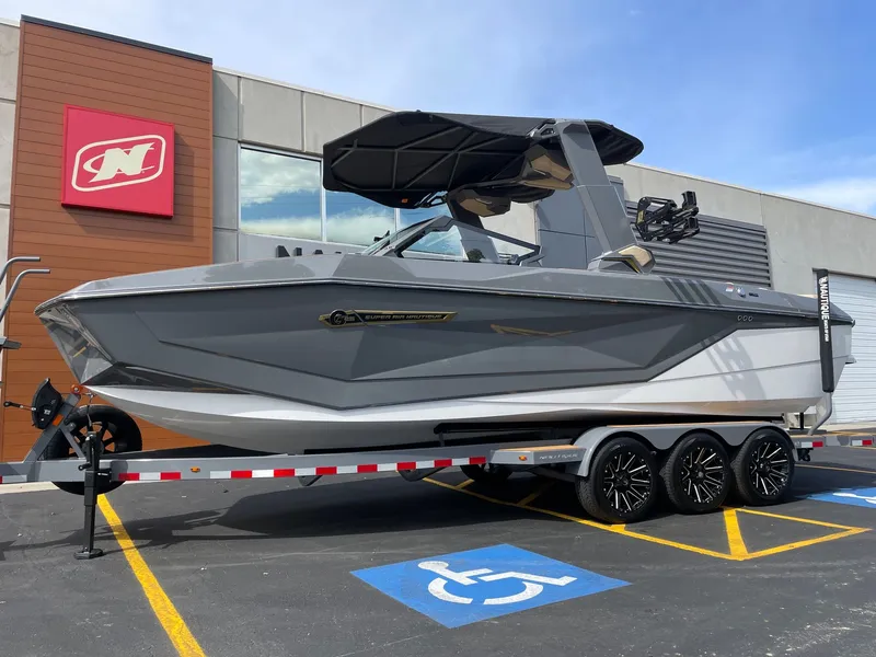 Slide: The Image of 2026 Nautique G25 boat on trailer in front of building. - 2