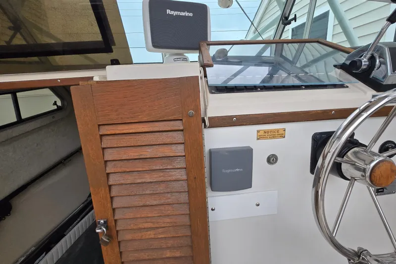 Slide: The Image of 1989 Sea Ox 250C boat dashboard with Raymarine equipment and wooden cabin door. - 14