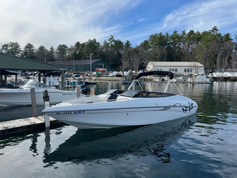 The Image of 2003 Crownline 225 LPX boat docked, calm water, wooded background. - 1