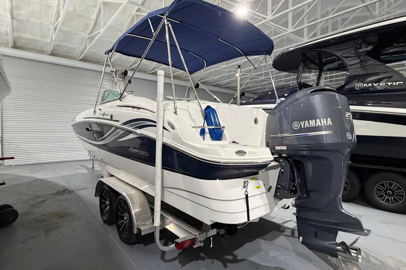 The Image of 2013 Hurricane SunDeck 2400 OB boat with Yamaha engine on trailer in indoor storage. - 0