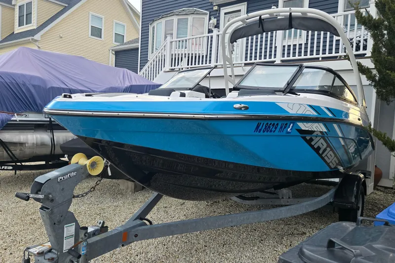 Slide: The Image of 2021 Yamaha Boats AR195 in blue, parked on a trailer near residential homes. - 3