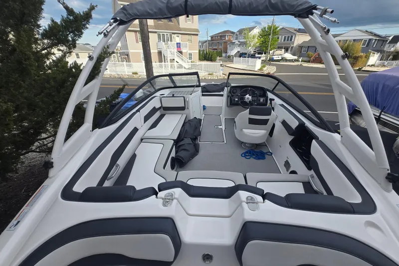 Slide: The Image of 2021 Yamaha Boats AR195 interior with seating and steering wheel, parked in a residential area. - 5