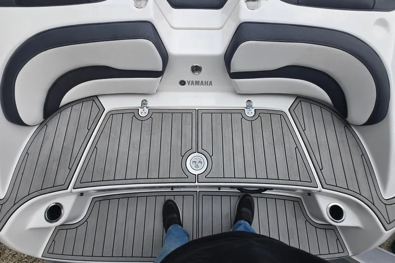 Slide: The Image of 2021 Yamaha AR195 boat deck with gray flooring and cushioned seating. - 9