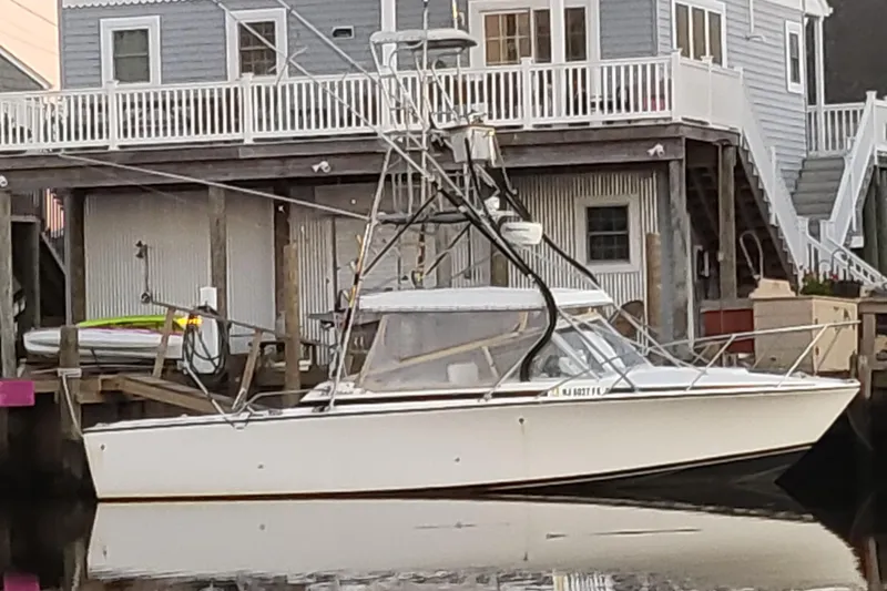 The Image of 1977 Bertram 28 Moppie boat docked near waterfront house. - 1
