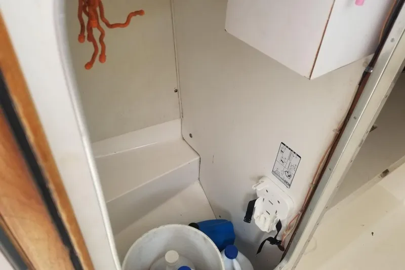 Slide: The Image of Interior of a 1977 Bertram 28 Moppie boat, featuring storage space and cleaning supplies. - 11