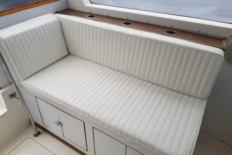 Slide: The Image of White cushioned seating on a 1977 Bertram 28 Moppie boat, featuring storage compartments. - 14