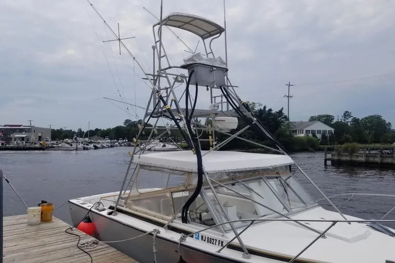 Slide: The Image of 1977 Bertram 28 Moppie boat docked at marina, featuring tall tower and calm waters. - 17