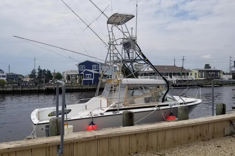 Slide: The Image of 1977 Bertram 28 Moppie boat docked by waterfront homes under cloudy sky. - 18