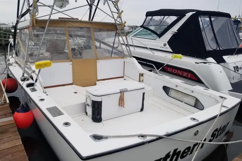 Slide: The Image of 1977 Bertram 28 Moppie boat docked, featuring spacious deck and fishing equipment. - 21