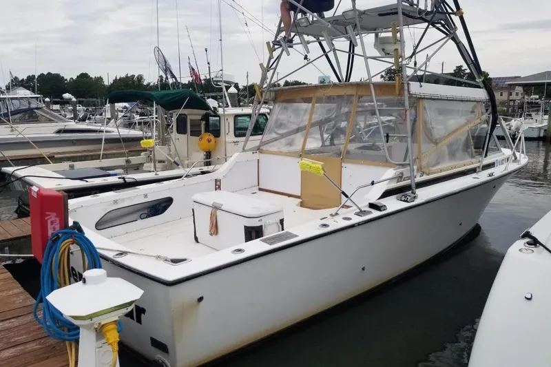 Slide: The Image of 1977 Bertram 28 Moppie boat docked at a marina, featuring a spacious deck and fishing equipment. - 22