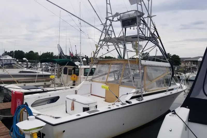 Slide: The Image of 1977 Bertram 28 Moppie boat docked at a marina, featuring a tall tower. - 23