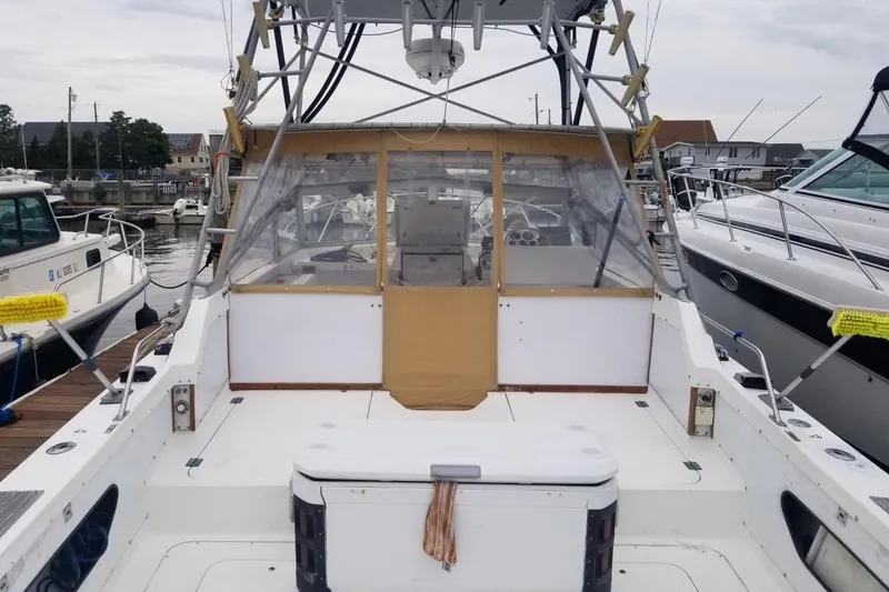 Slide: The Image of 1977 Bertram 28 Moppie boat docked at marina, featuring spacious deck and enclosed cockpit. - 24