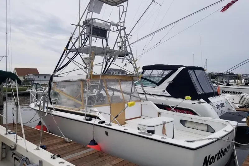 Slide: The Image of 1977 Bertram 28 Moppie boat docked at marina, featuring a tall fishing tower. - 25