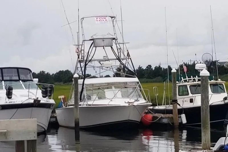 Slide: The Image of 1977 Bertram 28 Moppie boat docked, with "For Sale" sign, surrounded by other boats. - 26