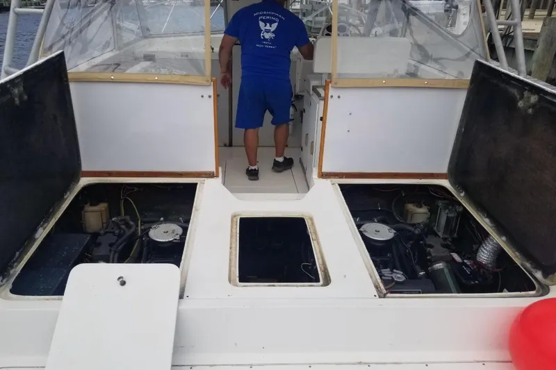 Slide: The Image of 1977 Bertram 28 Moppie boat with open engine compartments and person standing at helm. - 4