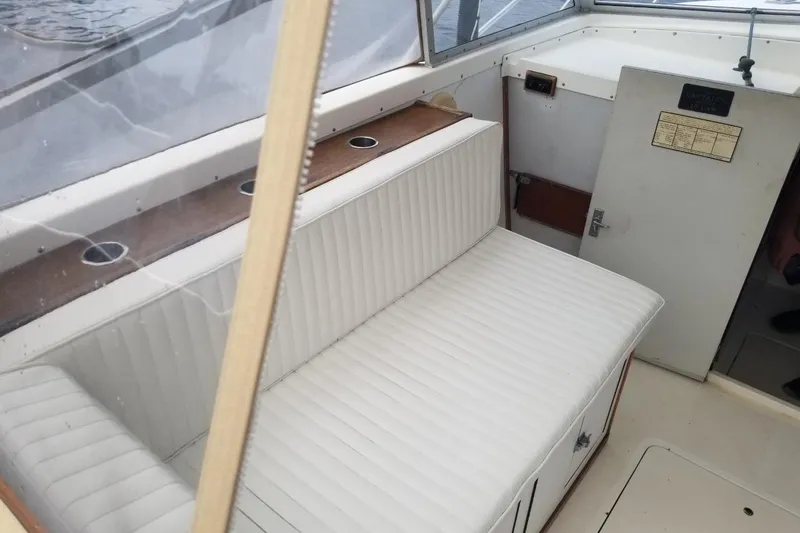 Slide: The Image of 1977 Bertram 28 Moppie boat interior with white cushioned seating and wooden accents. - 9