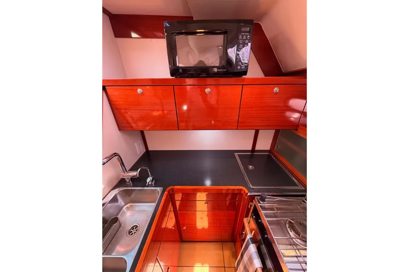 Slide: The Image of Compact kitchen in 2006 Hanse 461 yacht with microwave, sink, and wooden cabinetry. - 49