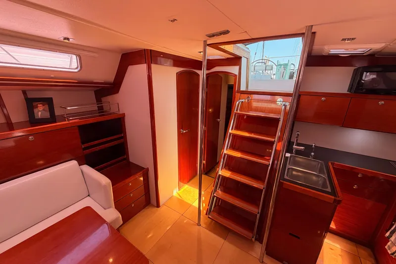 Slide: The Image of Interior of 2006 Hanse 461 yacht with wooden cabinetry, stairs, and compact kitchen area. - 77