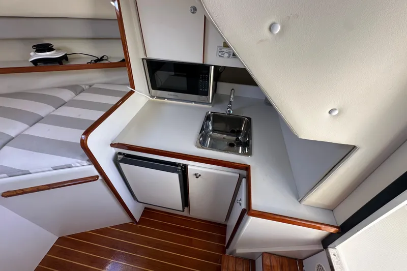 Slide: The Image of 1998 Tiara Yachts 2900 Coronet interior with kitchenette, sink, and striped seating. - 20