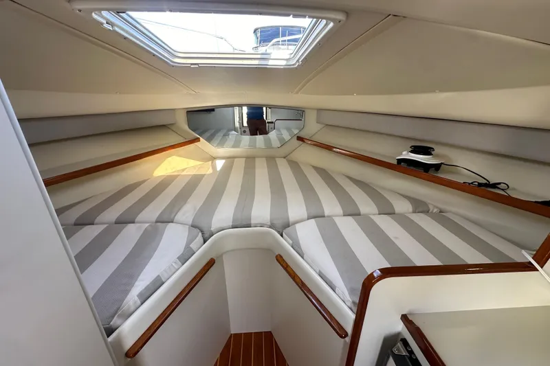 Slide: The Image of 1998 Tiara Yachts 2900 Coronet cabin interior with striped bedding and wooden accents. - 21