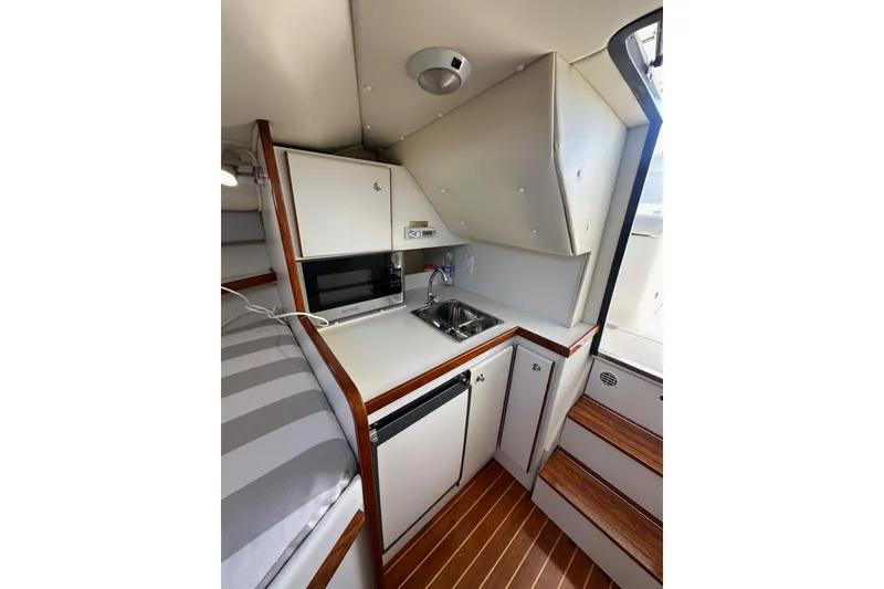 Slide: The Image of Compact galley in 1998 Tiara Yachts 2900 Coronet, featuring sink, microwave, and wooden accents. - 24