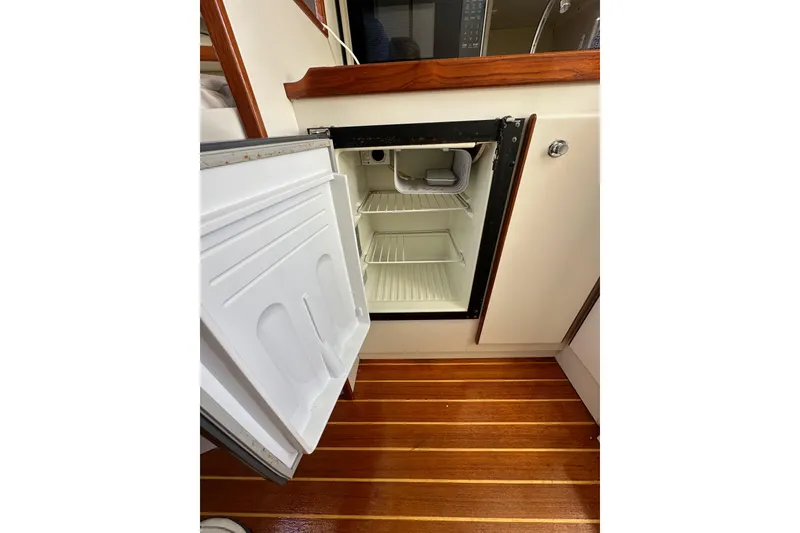 Slide: The Image of Open refrigerator inside 1998 Tiara Yachts 2900 Coronet, showcasing wooden flooring and compact design. - 25