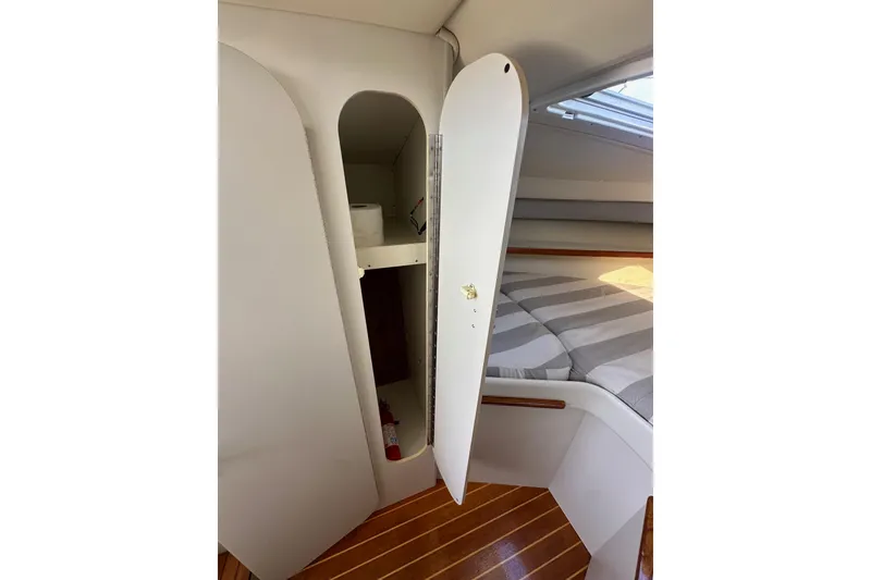 Slide: The Image of 1998 Tiara Yachts 2900 Coronet cabin interior with open storage and striped bedding. - 28