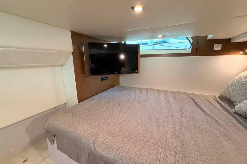 Slide: The Image of 2020 Cruisers Yachts 390 Express Coupe cabin with bed, TV, and window view. - 68