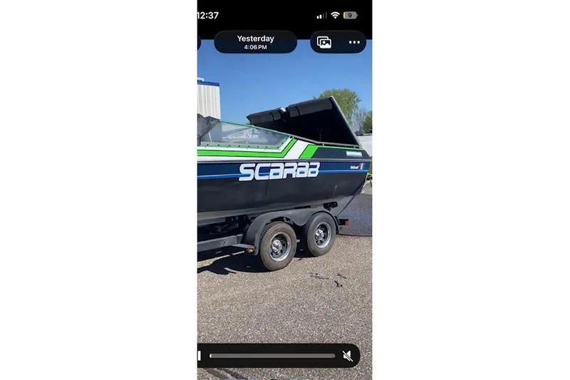 Slide: The Image of 1984 Wellcraft 22 Scarab boat on trailer, black with green accents, parked outdoors. - 9
