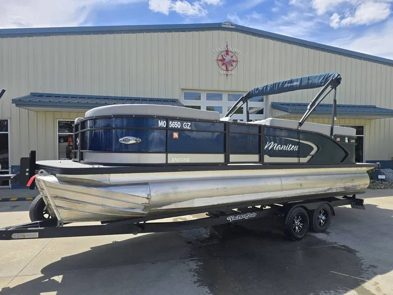 The Image of 2022 Manitou 23 Encore RF SHP pontoon boat in front of a building. - 1