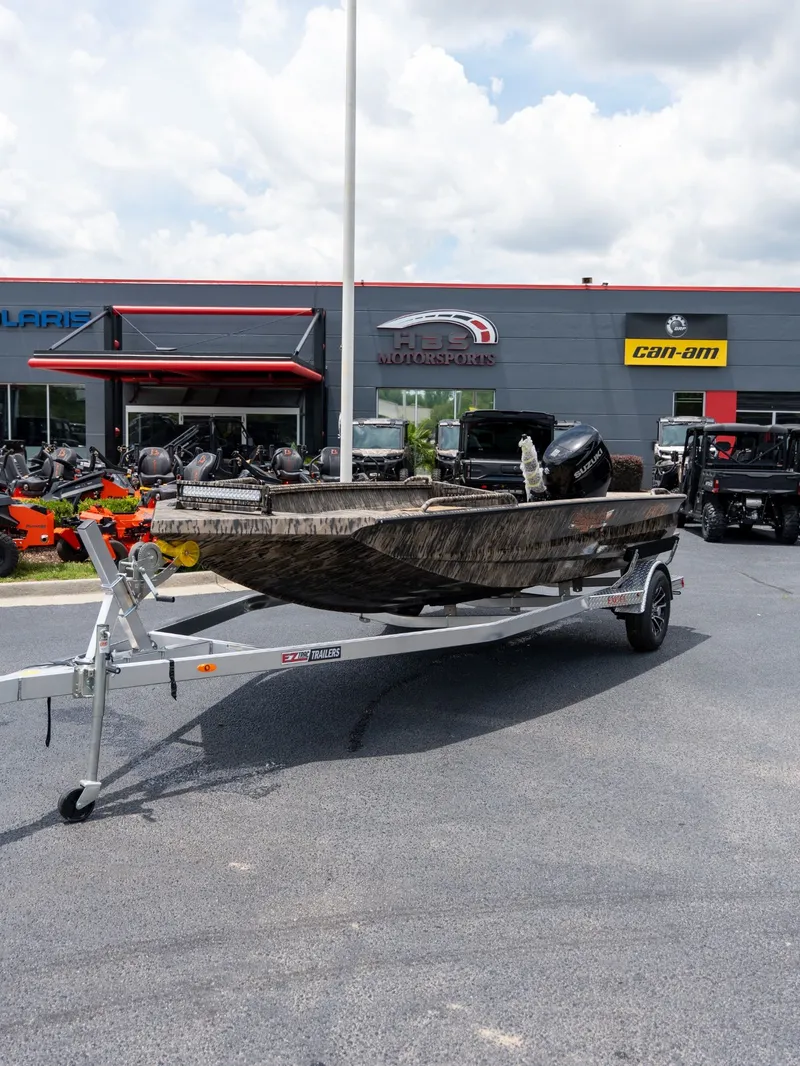 The Image of Excel 183 Tomahawk boat on trailer outside a motorsports store. - 1