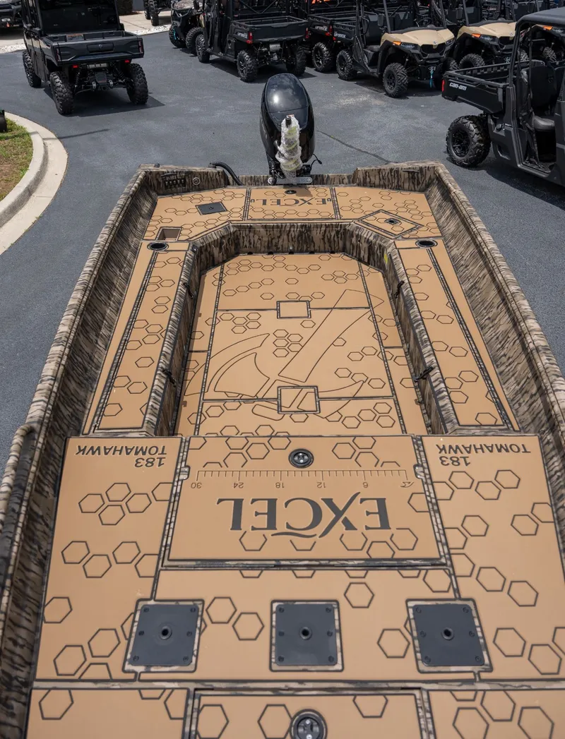 Slide: The Image of Excel 183 Tomahawk boat, 2026 model, parked with off-road vehicles. - 7