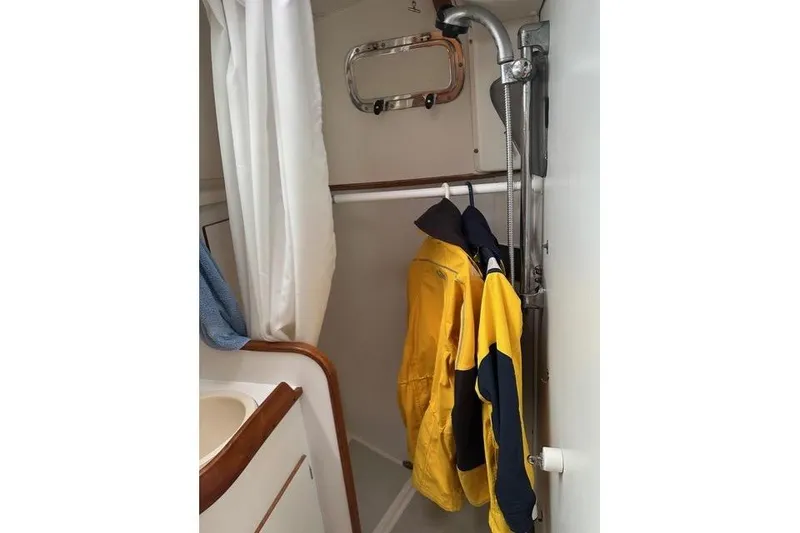Slide: The Image of Interior of a 1996 Freedom 35 sailboat bathroom with hanging yellow jackets. - 5