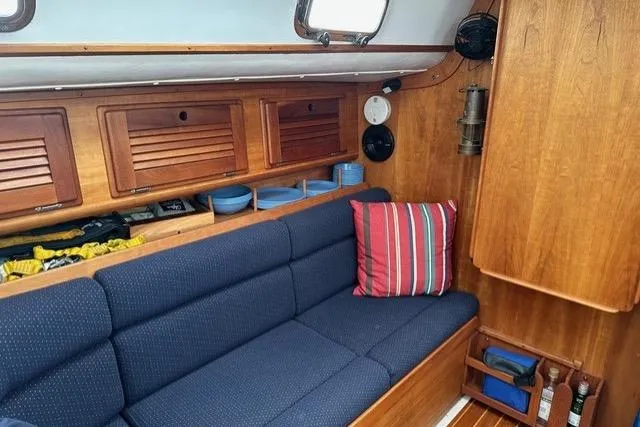 Slide: The Image of Cozy 1996 Freedom 35 sailboat interior with blue seating and wooden cabinetry. - 9