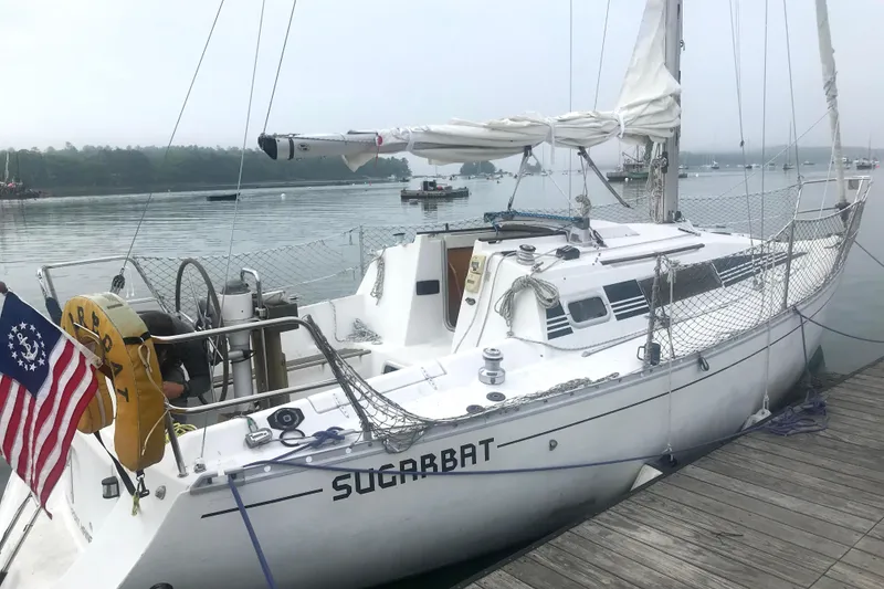 The Image of 1988 Beneteau First 285 sailboat docked, displaying American flag, calm waters in background. - 1