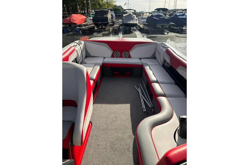 Slide: The Image of 2017 Axis T23 boat interior with red and gray seating, docked at a marina. - 2