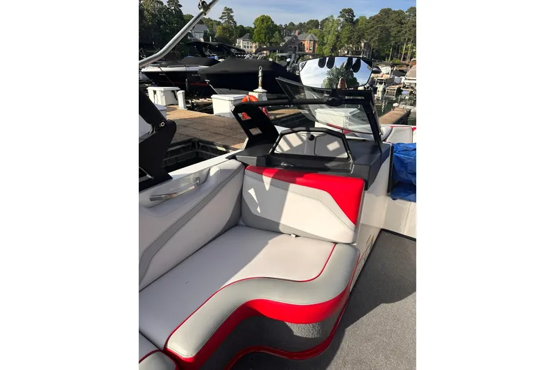 Slide: The Image of 2017 Axis T23 boat interior with red and gray seating at a marina. - 5