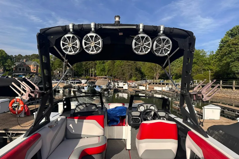 Slide: The Image of 2017 Axis T23 boat interior with red and gray seating, docked at a marina. - 6