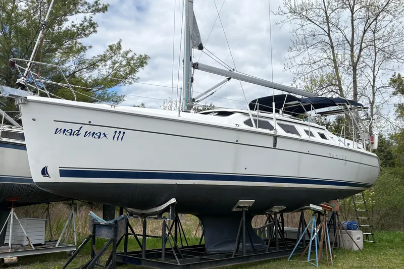 The Image of 2009 Hunter 41 Deck Salon sailboat on stands, named "Mad Max III," surrounded by trees. - 0