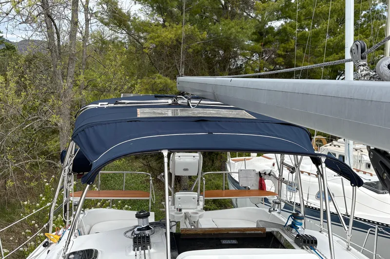 Slide: The Image of 2009 Hunter 41 Deck Salon sailboat with blue canopy, docked near trees. - 28